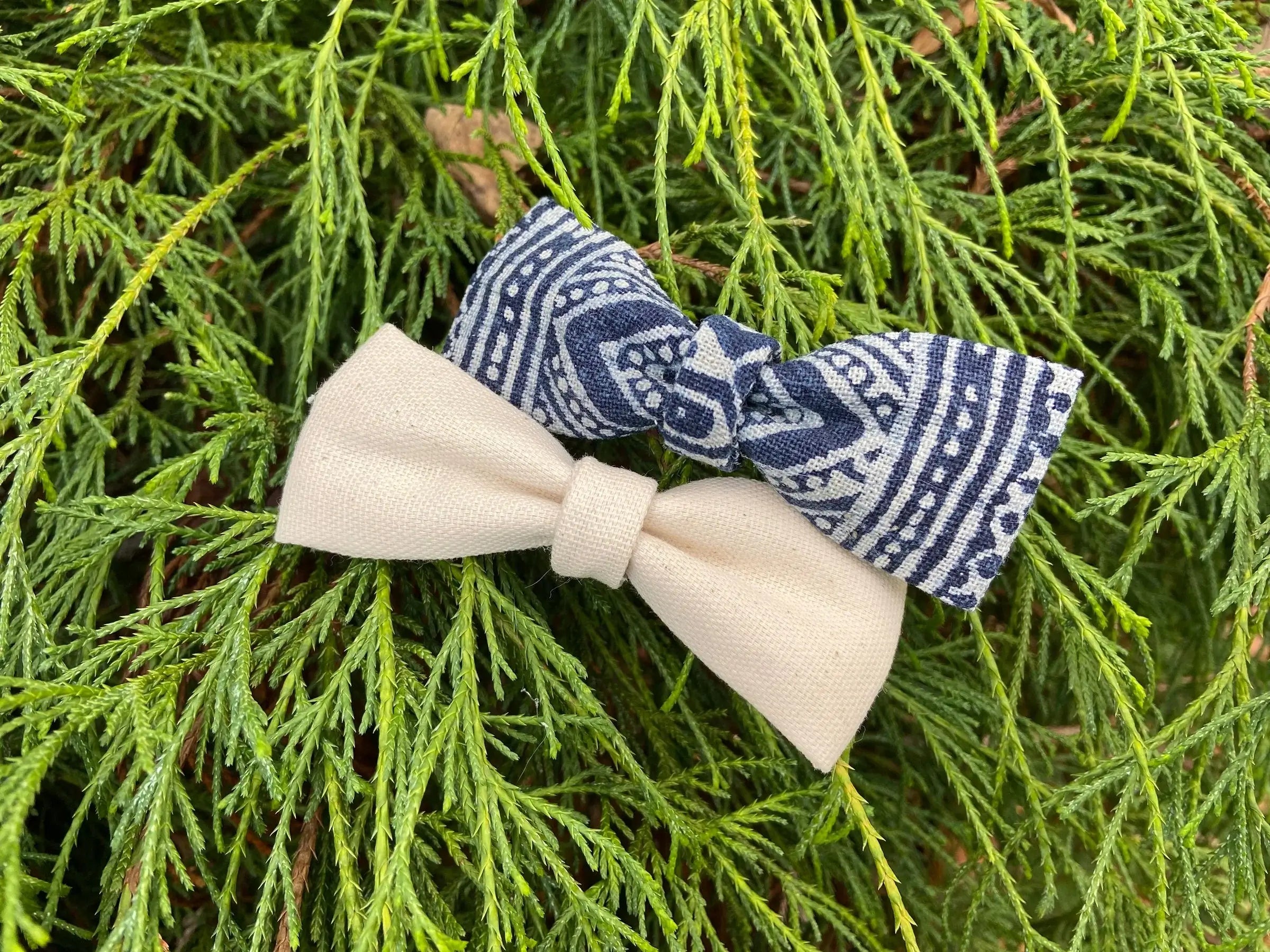 two bow ties on display resting on some greenery