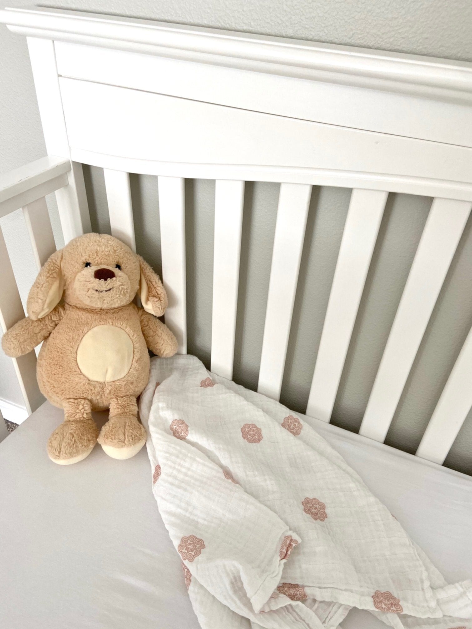 Muslin swaddle in a crib with a toy doll.